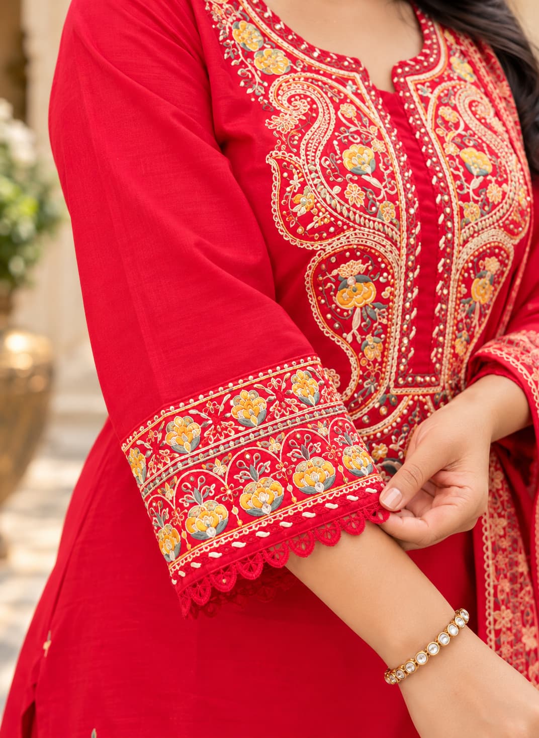 Close-up of multicolour thread embroidery on the sleeve cuff of a red cotton kurta